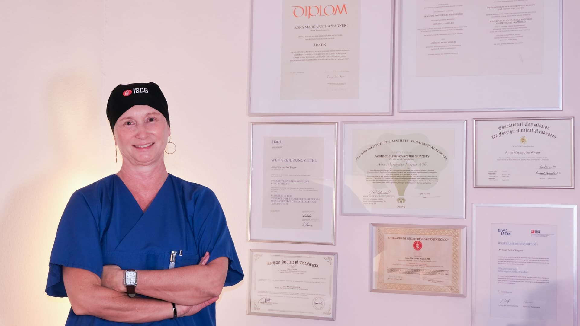 Dr. Wagner in scrubs in front of her wall of diplomas and certificates